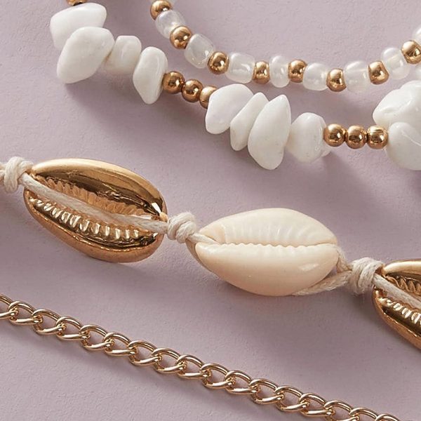 Un ensemble de bracelet chaine de cheville coquillage avec coquillages blancs et chaînes dorées.