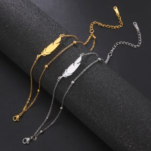 Trois bracelets de plumes en or et argent sur fond noir, comportant des bijoux.
