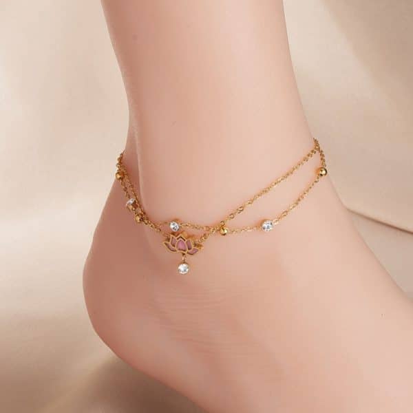 Un pied de femme orné d'un bracelet de cheville en or, mettant en valeur le bracelet de cheville lotus en acier.