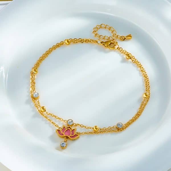 Un bracelet de cheville lotus en or sur une plaque blanche.