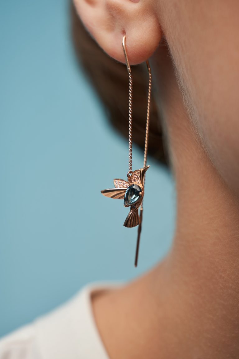 Une femme portant une paire de boucles d'oreilles avec un oiseau dessus.