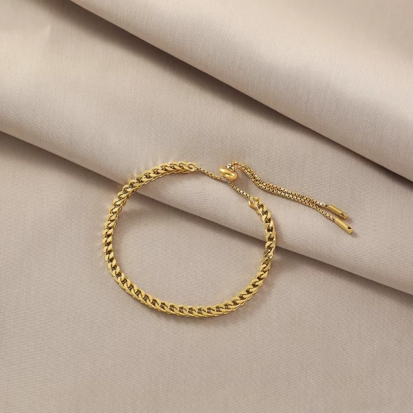 Un bracelet chaîne dorée sur un lin beige.