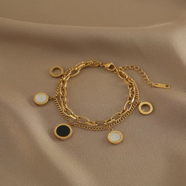 Un bracelet en or avec des cercles noirs et blancs.
