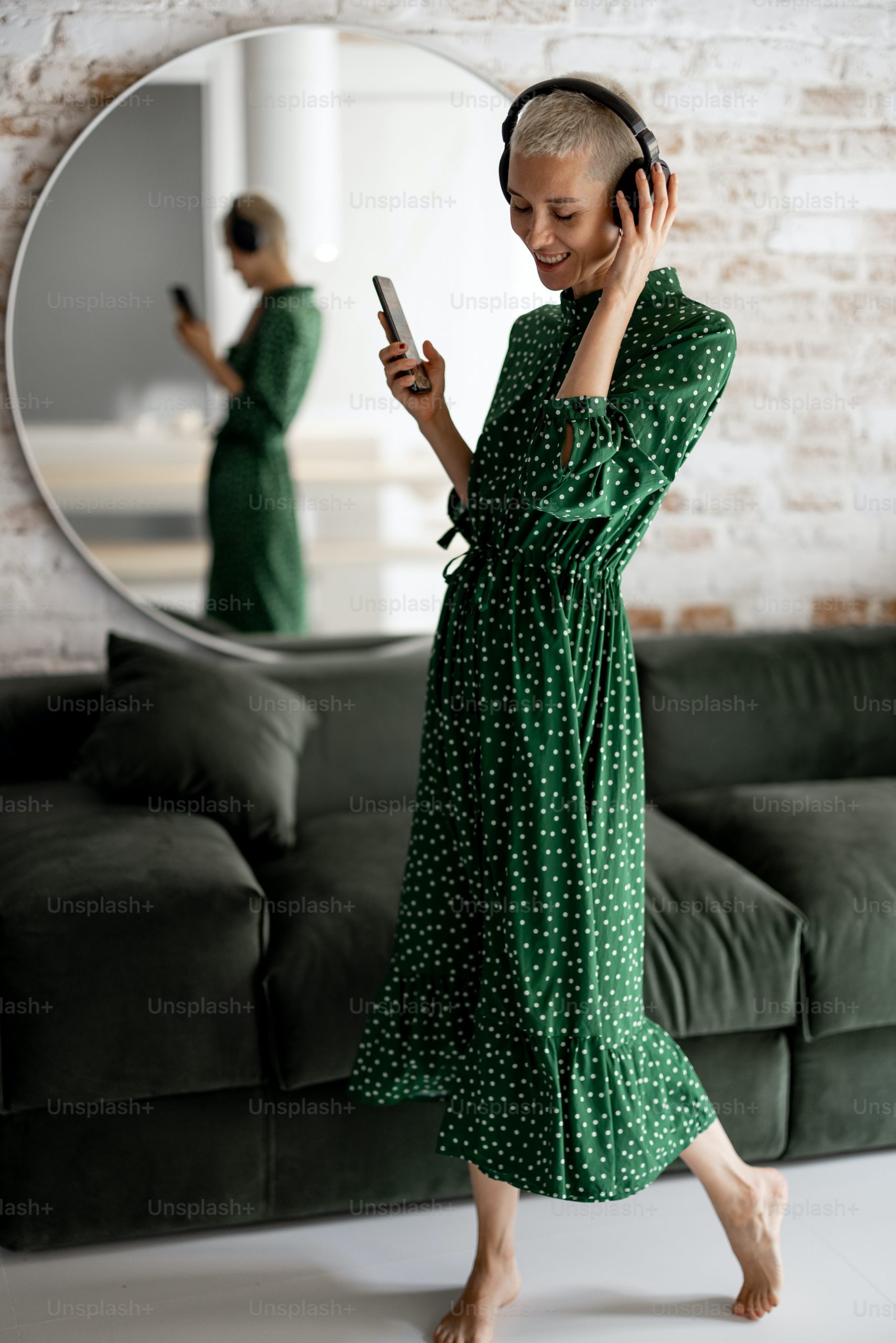 Une femme vêtue d'une robe verte à pois, écoutant de la musique tout en portant ses bijoux préférés.