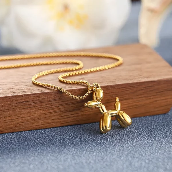 Un collier en acier inoxydable doré avec pendentif chien sur une table en bois.
