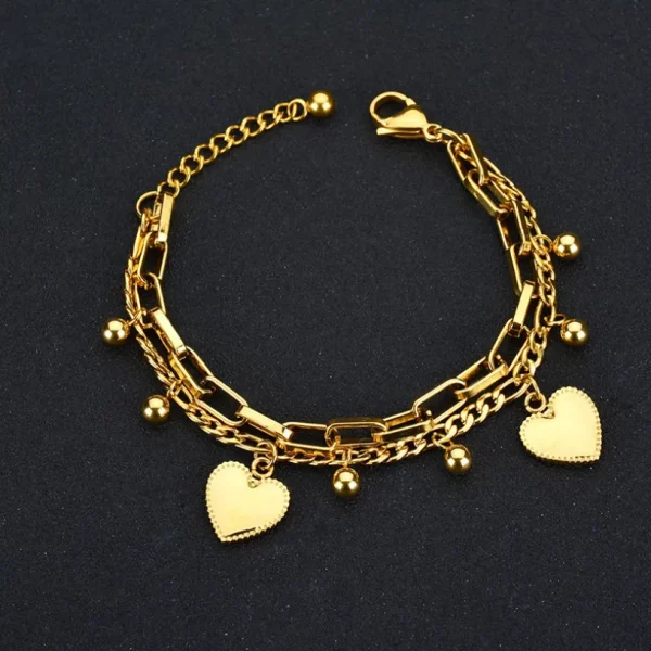 Un bracelet cœur en acier inoxydable pour femme avec des breloques.