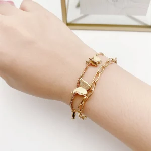 La main d'une femme tient un bracelet en chaîne en acier inoxydable avec pendentif papillon