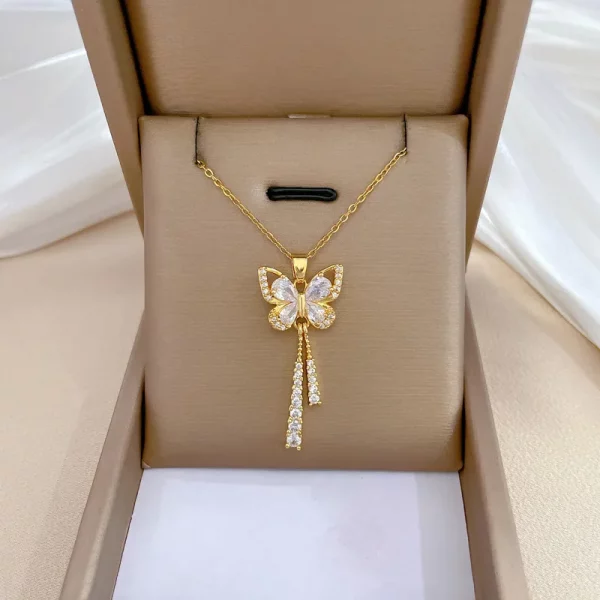 Un collier papillon diamant en acier doré serti de diamants dans une boîte.