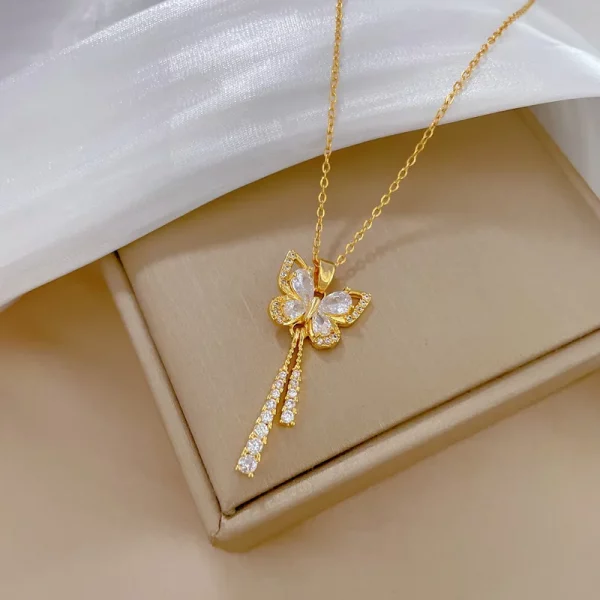 Un pendentif collier papillon diamant en acier doré attaché à un collier collier en or.