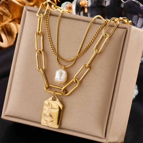 Un collier Collier Multirang en Acier Inoxydable Doré avec Pendentif Carré avec une perle dedans.