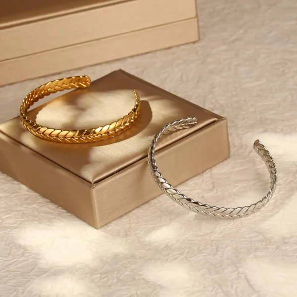 Une paire de Bracelet jonc acier inoxydable Style blé sur le dessus d'une boîte, mettant en valeur leur design élégant en acier inoxydable.