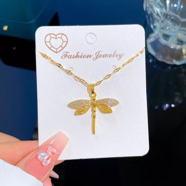 Un collier libellule en acier inoxydable doré sur une carte.
