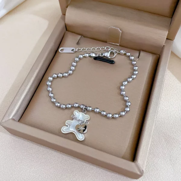 Un bracelet acier inoxydable perlé pendentif ours blanc dans un coffret cadeau.