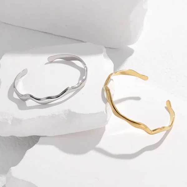 Une paire de bracelet jonc en acier inoxydable pour femme en or et argent en zigzag.