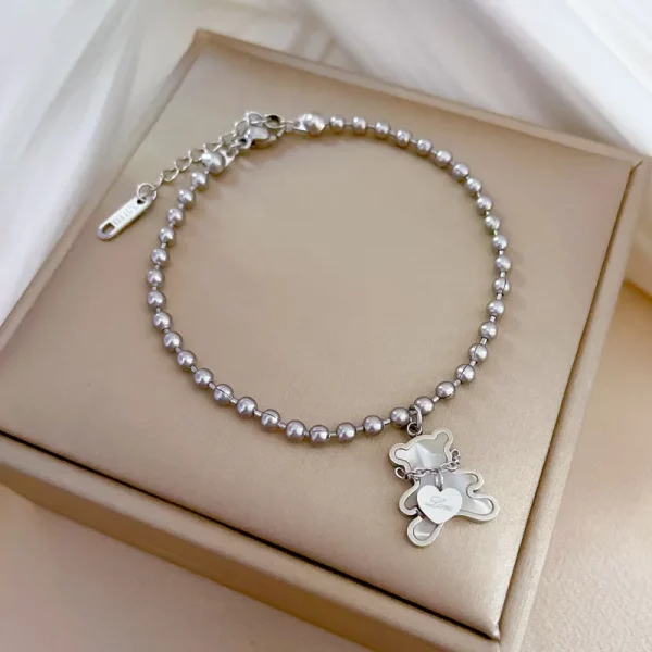 Un bracelet acier inoxydable perlé pendentif ours blanc avec une breloque ours en peluche.