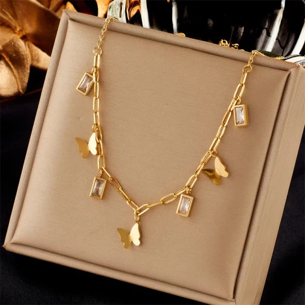 Un collier pendentif papillon chaîne en or avec des cristaux et une boîte.