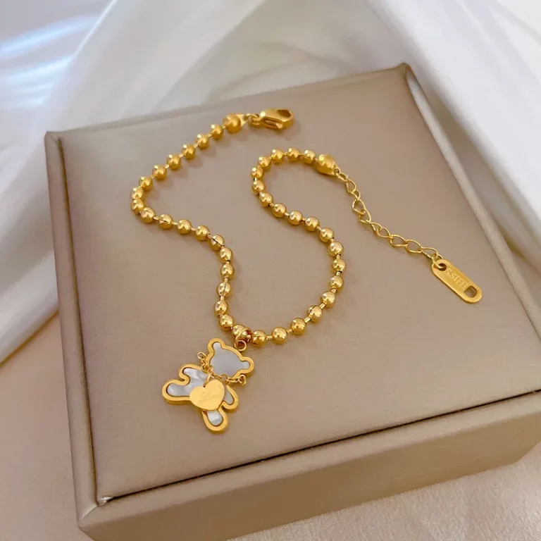 Un bracelet plaqué or acier inoxydable perlé pendentif ours blanc dans un coffret cadeau, avec un pendentif ours.
