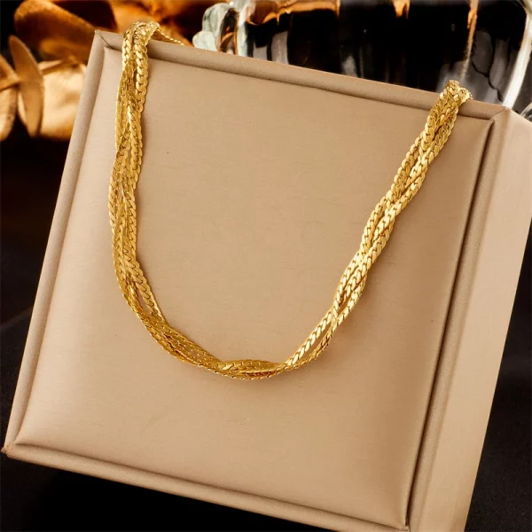 collier tressé en acier doré sur une boîte de bijoux