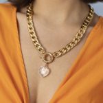 Une femme portant un haut orange et un collier acier inoxydable.