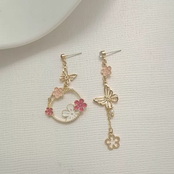 Une paire de boucles d'oreilles avec des fleurs roses et des papillons.