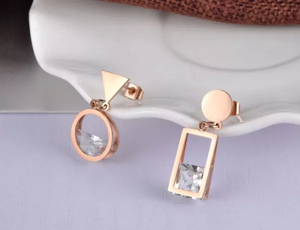 Une paire de boucles d'oreilles pendantes asymétriques rondes rectangle en or avec des diamants.