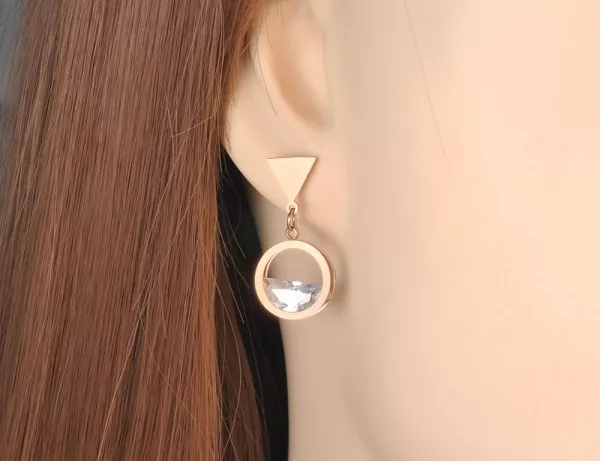 Une boucle d'oreille pendante asymétrique ronde rectangle avec une boucle d'oreille en diamant.