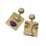 Une paire de boucles d'oreilles en or avec un visage et des lèvres.
