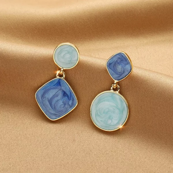 Une paire de Boucles d'Oreilles Asymétriques Carrées et Rondes avec des marbres bleus et blancs, de conception asymétrique.