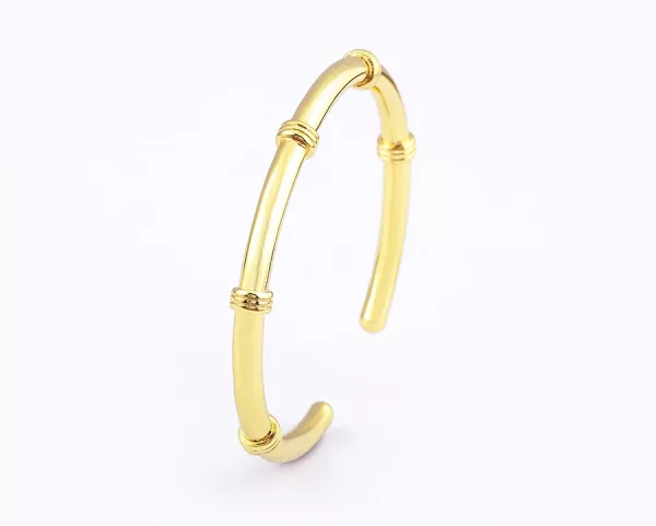 Un bracelet jonc ouvert femme doré en acier inoxydable sur fond blanc.
