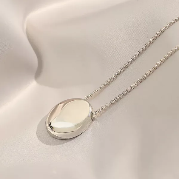 Un collier pendentif en argent Collier cailloux ovale en acier inoxydable sur fond blanc.