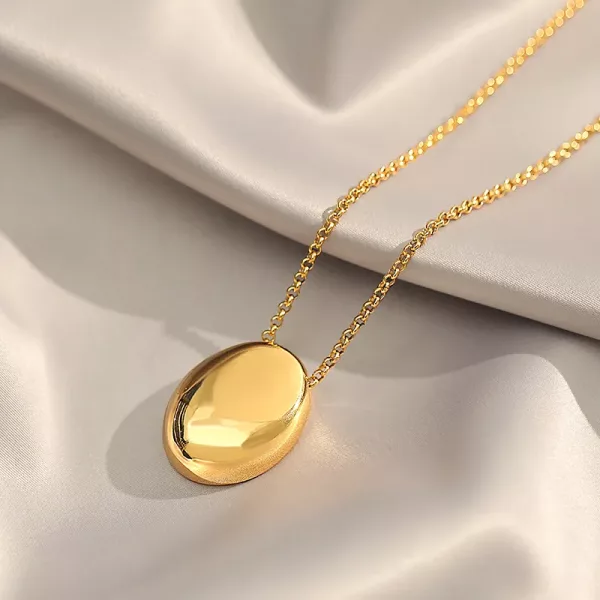 Un pendentif ovale plaqué or Collier cailloux ovale en acier inoxydable sur un collier en satin.