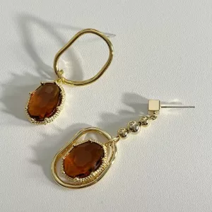Une paire de boucles d'oreilles en plaqué or avec une pierre marron.