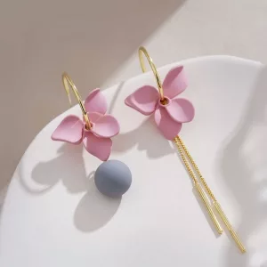 Deux boucles d'oreilles Boucle d'Oreille Fleur Asymétrique tendance à fleurs roses sur une assiette.
