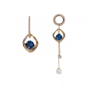 Une paire de boucles d'oreilles asymétrique avec une pierre bleue et des perles.