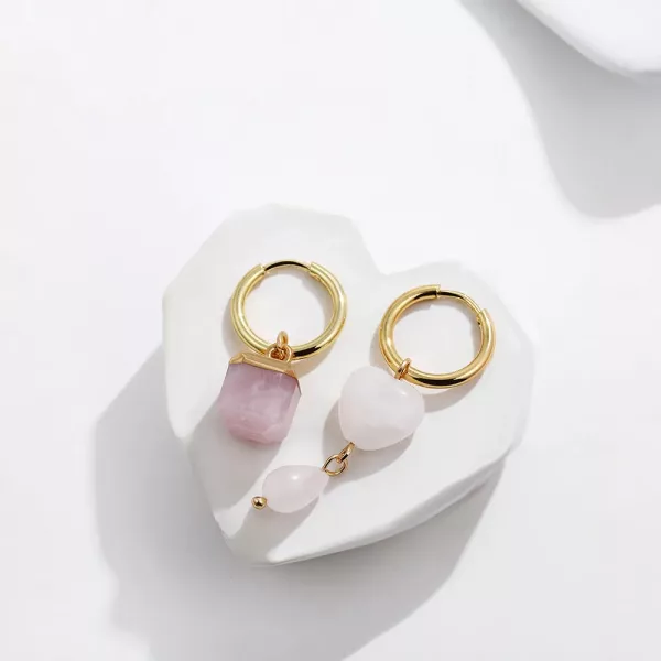 Une paire de boucles d'oreilles créoles en quartz rose sur une assiette blanche.