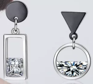La boucle d'oreille pendante asymétrique rond rectangle associe un rond et un rectangle tenant une pierre précieuse carrée sur une boucle d'oreille, tandis que l'autre combine un triangle et un cercle avec une pierre précieuse ronde à moitié exposée.