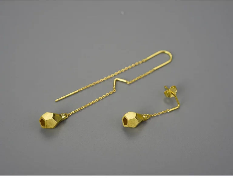 Une paire de boucles d'oreilles pendantes géométriques en or avec différents supports : l'un avec un enfile-chaîne, l'autre avec un fermoir à tige et papillon, tous deux dotés d'extrémités de forme hexagonale.