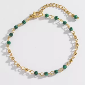 Un délicat bracelet en chaîne dorée avec de petites perles vertes régulièrement espacées et un fermoir réglable.