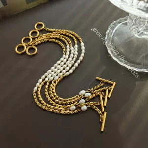 Des chaînes en acier avec des perles blanches sont disposées en lignes parallèles sur une surface sombre à côté d'un objet en verre. La lumière et les ombres sont visibles à travers l'arrangement.