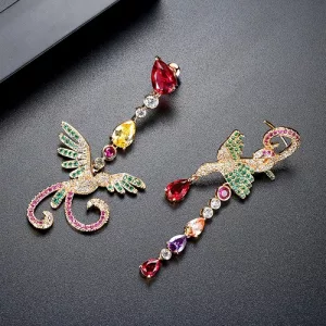Deux boucles d'oreilles ornées en forme d'oiseaux avec des pierres précieuses colorées en vert, rose, rouge et jaune, présentées sur une surface noire.