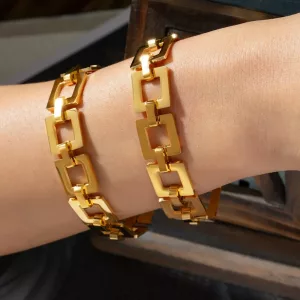 Deux bracelets à maillons géométriques en or, portés au poignet, photographiés sous un éclairage naturel.