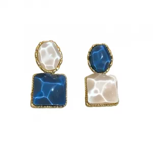 Une paire de boucles d'oreilles ornées de dorures, composées de pierres bleues et blanches de formes irrégulières, chacune comportant une petite pierre ovale sur le dessus et une plus grande pierre carrée en dessous.