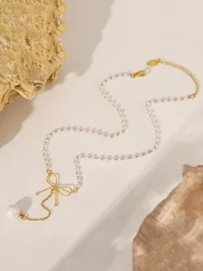 Un collier composé d'une chaîne en or, de petites perles blanches, d'un pendentif en forme de nœud en or et d'une seule grosse perle, présenté sur un fond clair rehaussé de touches de pierre.