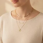 Collier multirang doré porté sur un haut crème